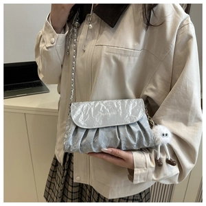 Detail of silver metallic pleated crossbody bag with chain strap and fuzzy charm