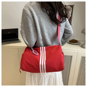Detail of red cylinder sports bag featuring white stripes and contrast braided drawcord