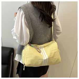 Detail of yellow striped barrel bag with woven zipper pull and side pocket for sport