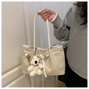 Detailed close-up of beige woven texture tote bag with a cute plush bear pendant