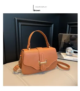 Detailed close-up of brown lychee grain leather handbag with gold metal buckle