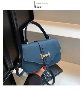 Detail of blue pebble leather handbag with gold T-shaped buckle and crossbody strap