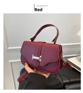 Close-up of wine red lychee leather texture and golden metal buckle on retro handbag