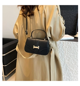 Close-up of black litchi grain leather bag featuring a iconic golden H-shaped metal buckle