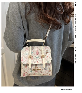Detail of white leather crossbody bag with cartoon bear and floral prints and gold hardware