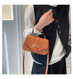 Close-up of caramel lychee leather handbag featuring a stylish gold metal flip lock