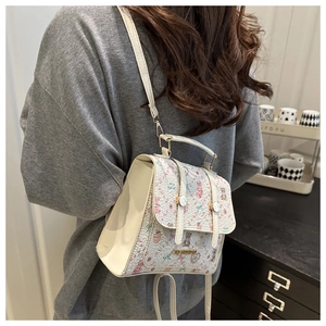 Detail of cream backpack with cartoon patterns worn on the shoulder in a lifestyle setting