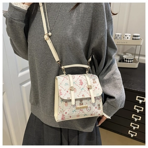 White crossbody bag with pink cartoon bear prints worn by model in a cozy interior