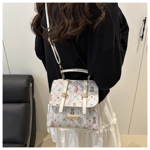 Detailed side view of white crossbody bag with cute cartoon prints and golden hardware