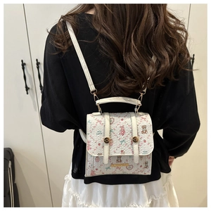 Close-up of mini floral backpack featuring pink bear prints and white faux leather