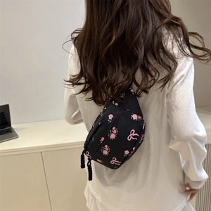 Sac à bandoulière noir en nylon avec imprimé roses roses porté par un mannequin chic
