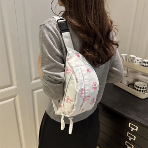 Sac bandoulière en nylon blanc avec imprimé fleurs et nœuds porté par un mannequin