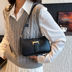 Chic black leather underarm bag with gold metal buckle shown on a model outfit