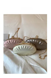 Detailed view of three satin shell bags in pink, cream and bronze with pearl clasps