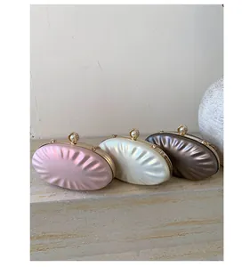 Detail of elegant pleated shell bags with pearl clasps in pink, white, and bronze