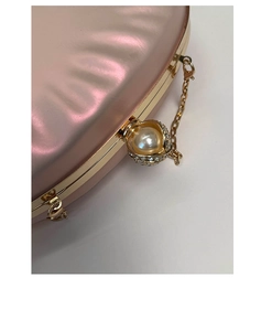 Detailed close-up of pearl and rhinestone clasp on pink iridescent evening clutch bag