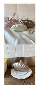 Detail of shell-shaped evening clutch bags with metallic texture and pearl clasp accent