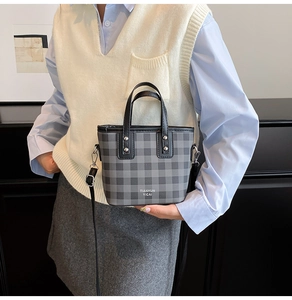 Close-up of a plaid bucket bag with silver hardware and adjustable leather shoulder strap