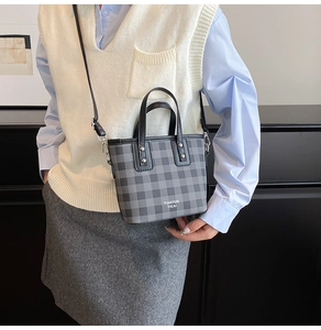Détail d'un petit sac cabas à carreaux avec bandoulière réglable porté à l'épaule