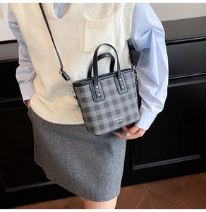 Detail of grey checkered mini bucket bag with leather handles and silver rivet studs