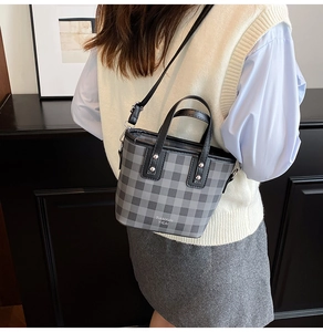 Detail of grey plaid bucket bag featuring leather handles and silver rivet accents