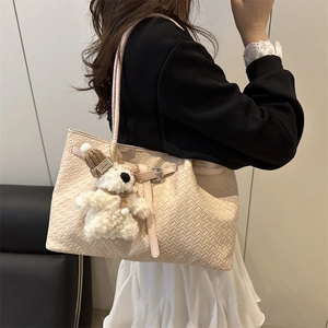 Chic beige woven tote bag for women featuring a plush bear charm and spacious interior