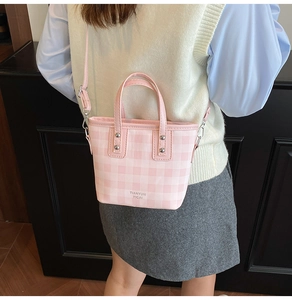 Detail of pink plaid bucket bag with adjustable strap worn as a crossbody purse