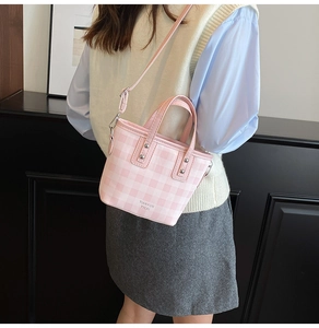 Detailed view of a pink plaid bucket bag with adjustable strap and metallic rivets