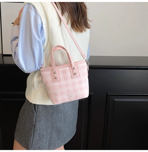 Pink and white checkered crossbody bag shown on model with silver rivet details