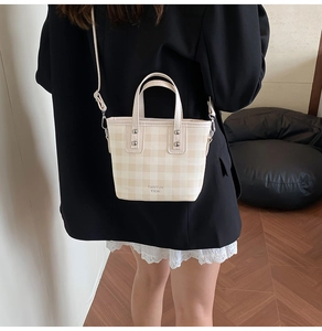 Détail du sac seau à carreaux beige avec bandoulière amovible porté par un mannequin