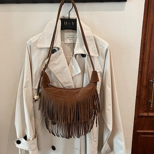 Dettagli di una borsa a spalla in pelle scamosciata marrone con frange e perline in legno