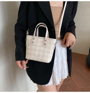 Details einer karierten Beuteltasche mit verstellbarem Riemen und silbernen Nieten