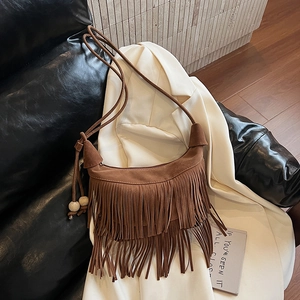 Dettaglio della borsa a mezzaluna in camoscio marrone con frange e perle in legno