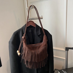 Dettaglio della borsa a spalla in pelle scamosciata marrone con frange e perle in legno