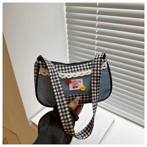 Detailed view of blue denim bag with black and white plaid straps and lace details