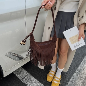 Dettaglio borsa hobo in pelle scamosciata marrone scuro con frange e fascino boho