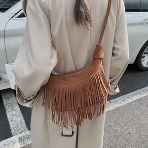 Dettaglio borsa a tracolla in pelle scamosciata marrone con frange e trench beige