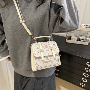 White PU crossbody bag with cartoon prints and pearl strap details on a grey sweatshirt