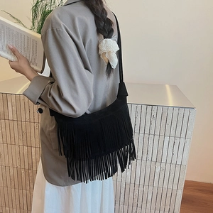 Dettaglio della borsa a spalla in pelle scamosciata nera con frange lunghe stile boho