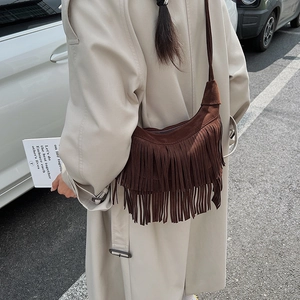 Vista dettagliata della borsa con frange in pelle scamosciata marrone con un trench beige