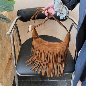 Dettaglio borsa con frange in camoscio marrone caramello e accenti di perline di legno