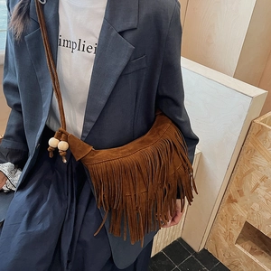 Dettaglio borsa a mezzaluna in camoscio marrone con lunghe nappe e perle di legno