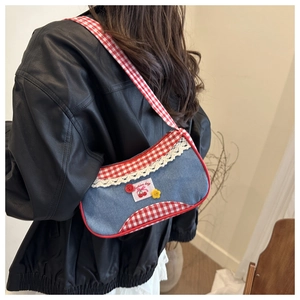 Close-up of blue denim and red plaid patchwork bag with white lace trim and cherry patch