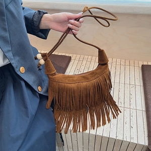 Dettaglio borsa a tracolla in pelle scamosciata marrone con frange e perle di legno
