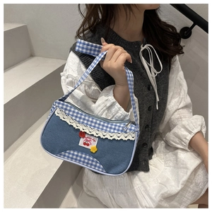 Close-up of blue denim and plaid handbag with delicate lace trim and cherry patch