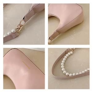 Detail view of pink PU leather crescent bag with pearl strap and gold hardware