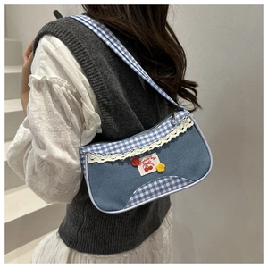 Detail of blue denim shoulder bag with lace trim, gingham patterns and floral accents