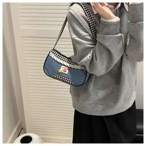 Detail of blue denim and checkerboard underarm bag with lace trim and cherry patches