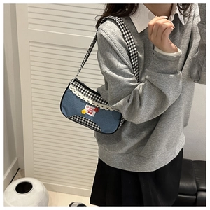 Detail of shoulder bag with blue denim, plaid fabric, lace trim and cherry embroidery