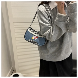 Detail of the blue denim and plaid shoulder bag with cherry patches and lace trim
